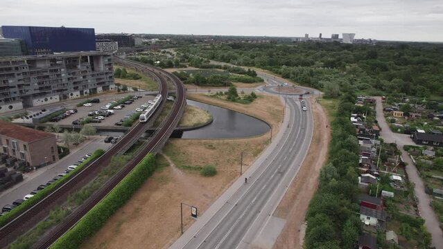 An urban area where the metro runs above ground, offering a captivating view of the bustling traffic on the roads, a roundabout, and the backdrop of nature in the distance
