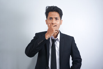 Young handsome Asian man wearing suit standing over isolated white background shocked covering mouth with hands for mistake. Secret concept.