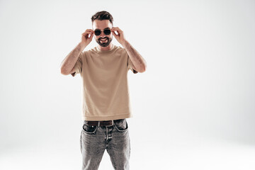 Portrait of handsome smiling stylish hipster lambersexual model. Sexy man dressed in T-shirt and jeans. Fashion male isolated on white background in studio. In sunglasses