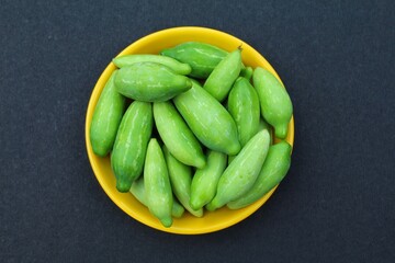 Ivy gourd in a plate on black background top view 