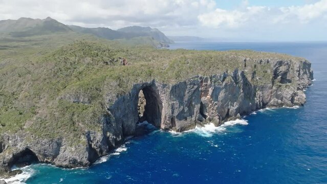 Aerial establishing shot of beautiful Cabo Cabron Nationalpark with natural arches, steep cliffs and crashing waves of blue Caribbean sea during cloudy day - panorama view