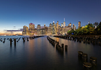 Beautiful Sunset and Lower Manhattan skyline with East River and New York City. Twilight with Reflections and Abandoned Pier at Sunset from Brooklyn Bridge Park