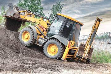 Powerful wheel loader or bulldozer on sky background. Loader pours crushed stone or gravel from the bucket. Powerful modern equipment for earthworks and bulk handling.