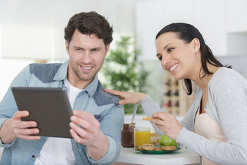 couple in home kitchen using electronic tablet