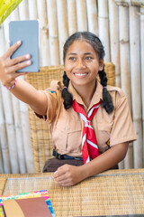 Schoolgirl dress uniform with red and white tie and ponytails looking at a tablet
