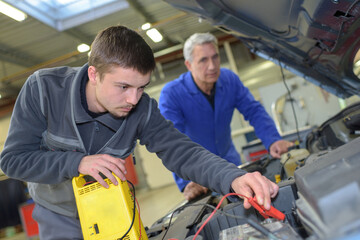 Fototapeta na wymiar apprentice mechanic in auto shop working on car engine