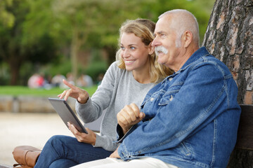 daughter with her father using tablet in the park