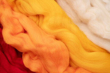 White, yellow, beige and red merino wool for felting as background texture