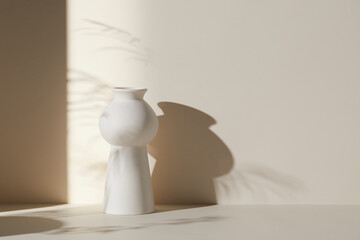 A room with various objects such as warm sunlight, shadows of grass leaves, a vase on a table, and cups