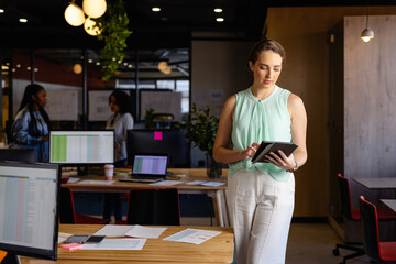 Caucasian casual businesswoman using tablet in office