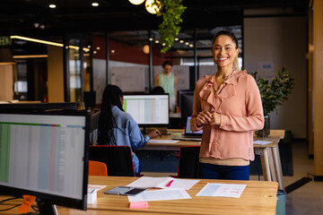 Portrait of happy biracial casual businesswoman in office