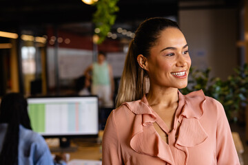 Portrait of happy biracial casual businesswoman in office