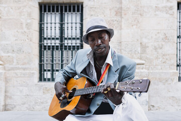 Black Man musician playing guitar on the street in La Havana in Latin America, Afro american and caribbean people