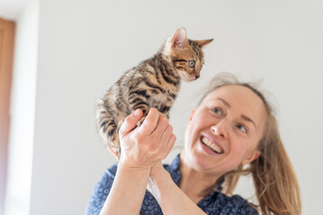 Close up of a blond woman happy playing with a kitten