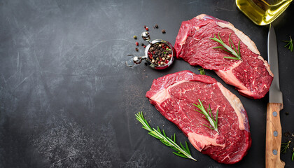 Raw beef steak with rosemary and spices on dark background. Top view