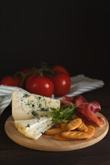 Cheese and cold cuts on a wooden tray on a wooden table