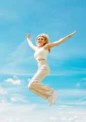 Obraz premium Young blond woman jumping high in the air. Lifestyle, freedom, lightness and happiness. 