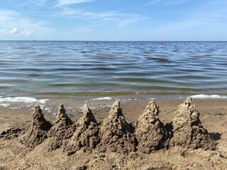 Fototapeta na wymiar Башенки из песка на пляже у воды