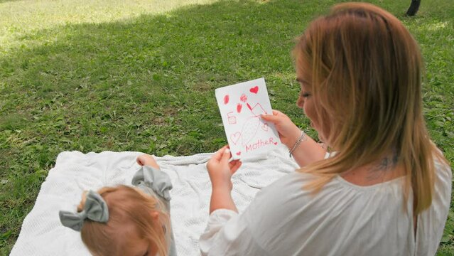 cute little girl gives mom a painted card and flowers happy mother's day happy family carefree childhood