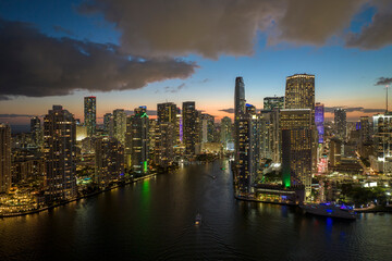 Fototapeta premium View from above of brightly illuminated high skyscraper buildings in downtown district of Miami Brickell in Florida, USA. American megapolis with business financial district at night