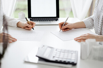 Two accountants using a laptop computer for counting taxes at white desk in office. Teamwork in business audit and finance