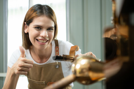 Portrait of a young woman working with a coffee roaster machine
