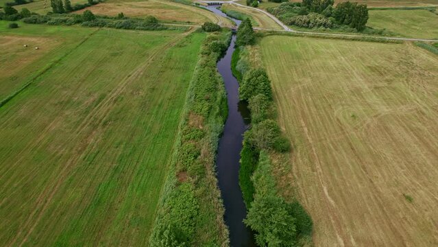 Flying over a river to reveal a building and a bridge in Polish nature reserve "Beka".