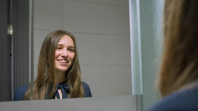Medium shot Caucasian woman smiling, gives herself high-five in mirror