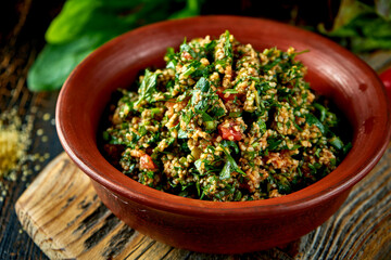 Georgian tabbouleh salad with mint, onion and bulgur in a clay dish. Dark background
