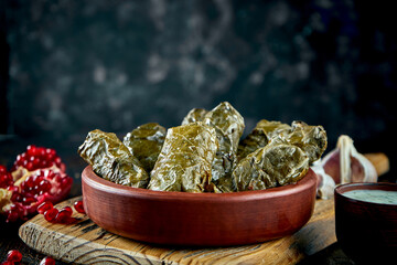 Dolma in grape leaves stuffed with rice and minced meat with white sauce in a clay dish. Georgian cuisine