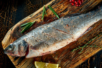 Marinated fresh sea bass with spices and lemon on a wooden board