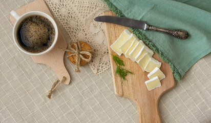 Breakfast - a cup of coffee, cookies and bru cheese on a cutting wooden board