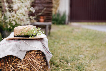 A straw hat with flowers lies on a bale of hay. Courtyard of a country villa. Rest in peace and tranquility.