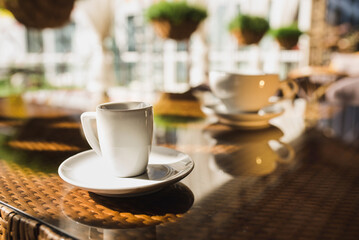 Cups of coffee and tea are on a glass table in the gazebo. Served for tea. table on the summer terrace of the cafe. morning ritual before work day. Rest between work and coffee break