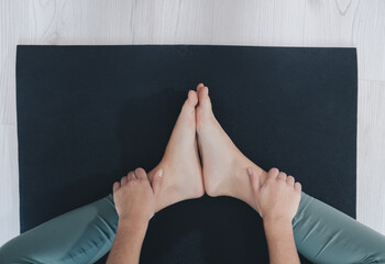 Legs of faceless barefoot person on mat during workout