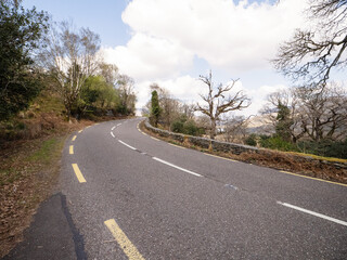 Fototapeta na wymiar Small asphalt road with stunning nature scenery in county Kerry, Ireland. Amazing Irish landscape by a popular travel rout for tourist. Warm sunny day cloudy sky. Sightseeing and explore wild scenery