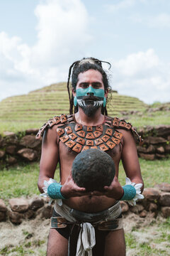 Mayan man in warrior costume and spooky face mask in countryside