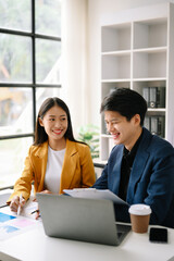 Two  Asian business  man and woman workers talking on the smartphone and using laptop Professionals in Teamwork  Finance, Marketing, and Success