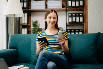 Obraz premium Confident Caucasian woman with a smile standing holding notepad and tablet in living room on the sofa at office