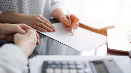 Woman accountant using a calculator and laptop computer while counting taxes for a client. Business...