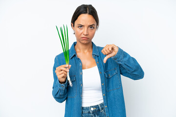 Young hispanic woman holding chive isolated on white background showing thumb down with negative expression