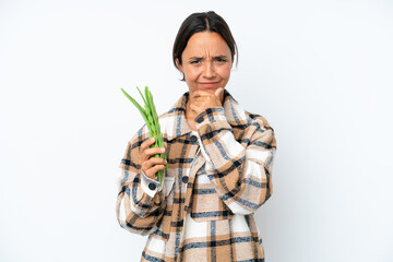 Young hispanic woman holding a green beans isolated on white background having doubts