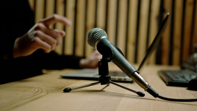 close-up sound engineer in home recording studio checks microphone taps on it with finger listens to sound