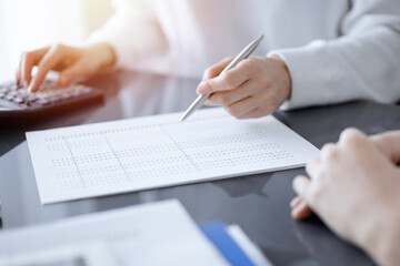 Woman accountant using a calculator and laptop computer while counting taxes for a client. Business audit concepts