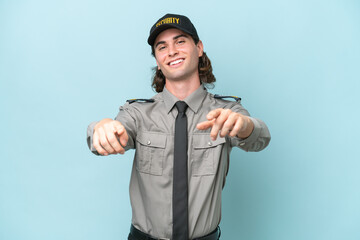 Young safeguard man isolated on blue background points finger at you while smiling