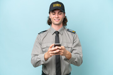 Young safeguard man isolated on blue background sending a message with the mobile