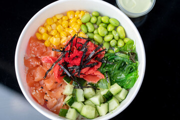 Hawaiian cuisine, poke bowl in disposable dishes. Rice combined with fish and fresh vegetables