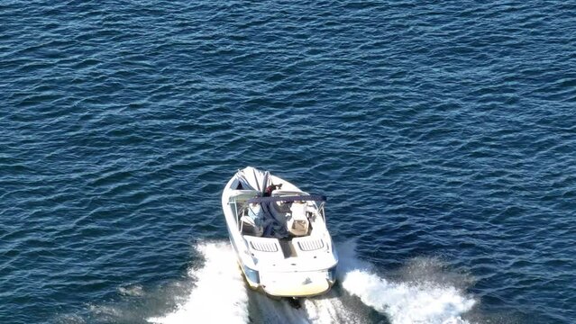 people driving a speed boat quickly on a bright blue water lake in california with a dog on board telephoto AERIAL DOLLY