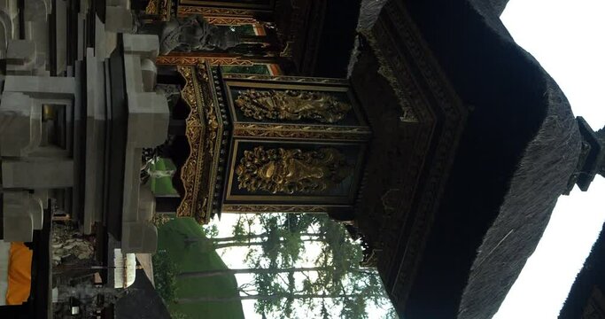 Vertical slow motion establishment shot of temple building at pura tirta empul water temple in ubud on bali indonesia. view of Bale Kulkul a balinese pavilion