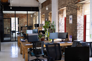 Empty creative office room with computers on desks and glass wall with notes